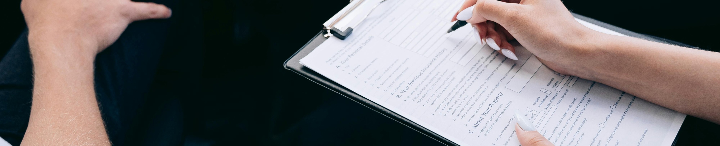 Osoba trzymająca notatnik, obok druga, siedzą w aucie