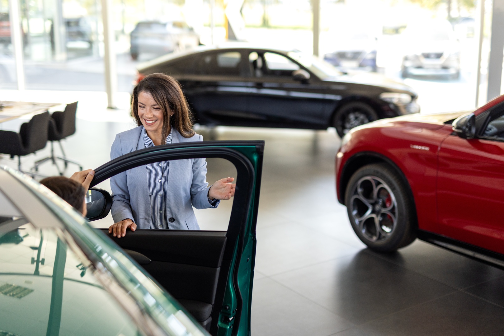 Mężczyzna wysiadający z auta w salonie rozmawia z kobietą