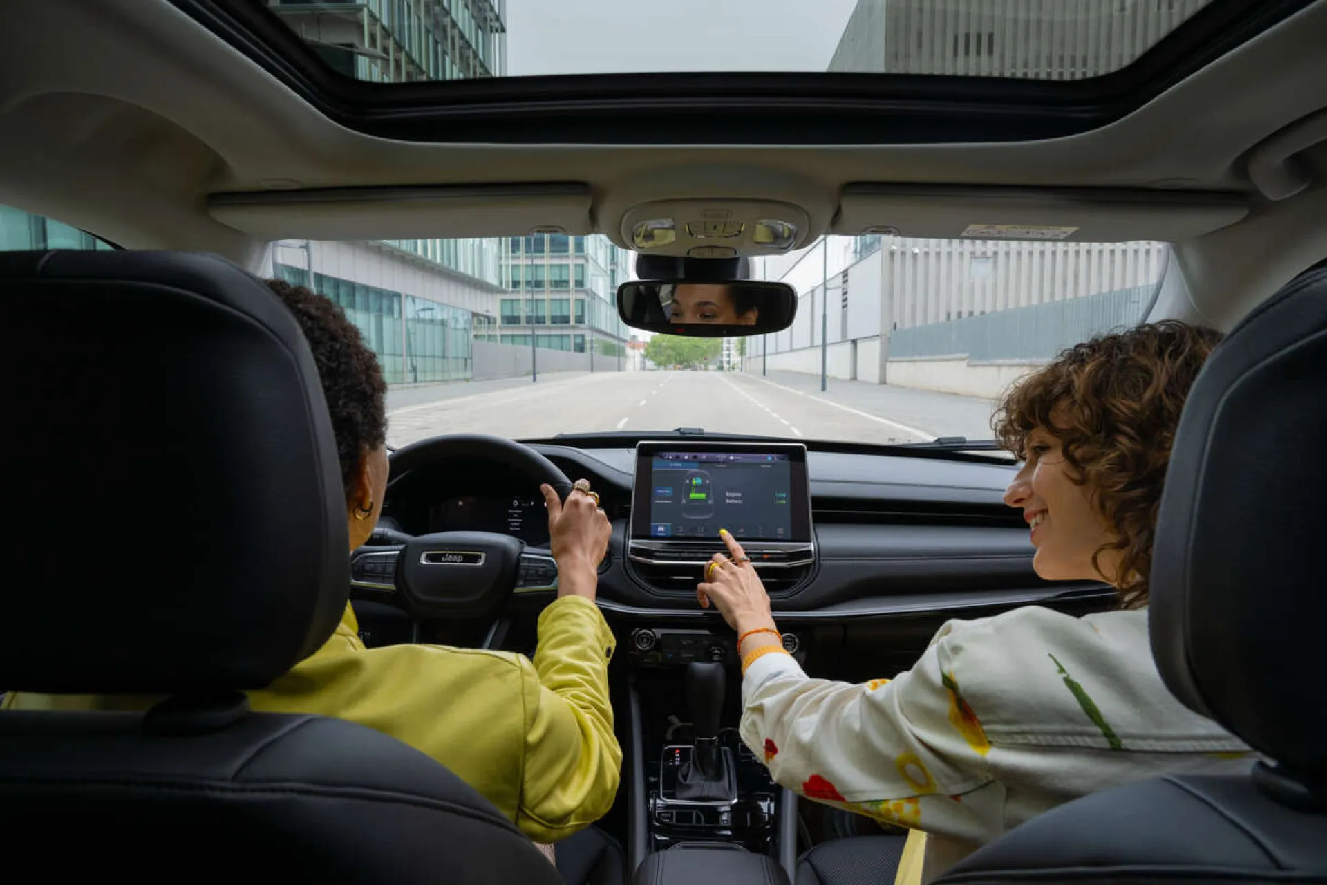 Dwie kobiety w aucie, jedna prowadzi, druga obsługuje panel dotykowy
